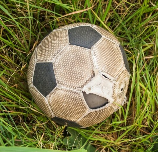 old soccer ball on the green grass top view 1024x682